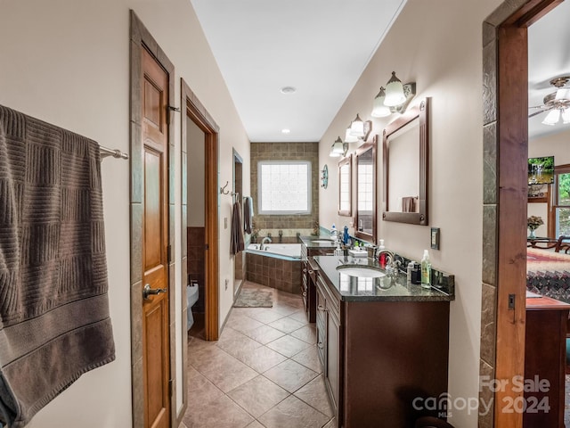 bathroom featuring a wealth of natural light, tile flooring, ceiling fan, and tiled bath