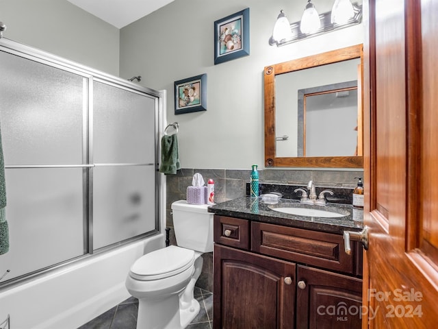 full bathroom with combined bath / shower with glass door, vanity, toilet, and tile floors