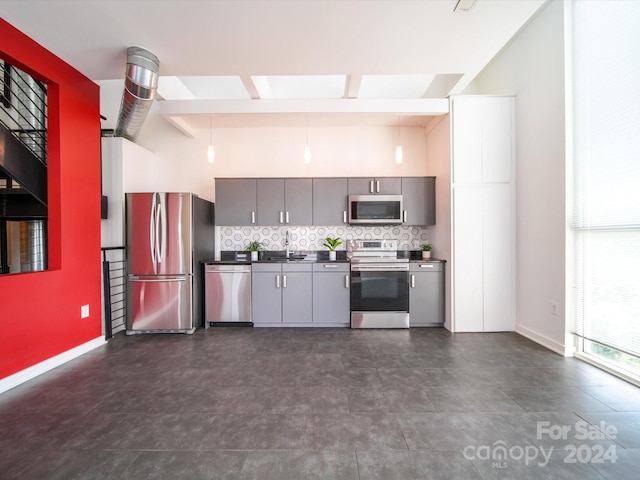 kitchen with appliances with stainless steel finishes, backsplash, sink, a high ceiling, and gray cabinets