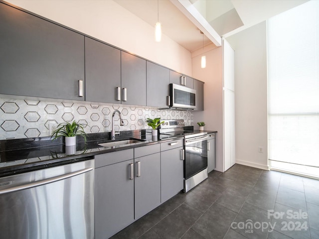 kitchen with pendant lighting, gray cabinetry, backsplash, sink, and appliances with stainless steel finishes