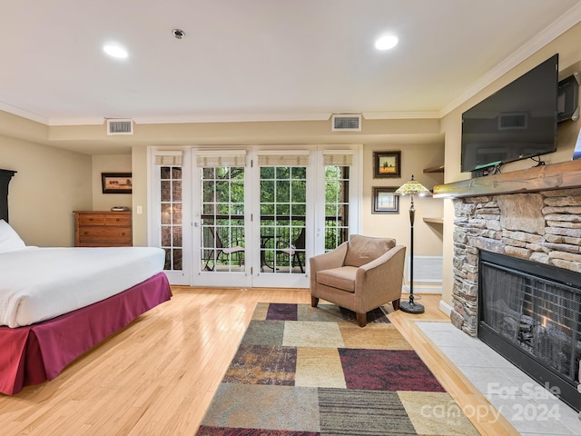 bedroom featuring access to exterior, a fireplace, light hardwood / wood-style floors, and ornamental molding