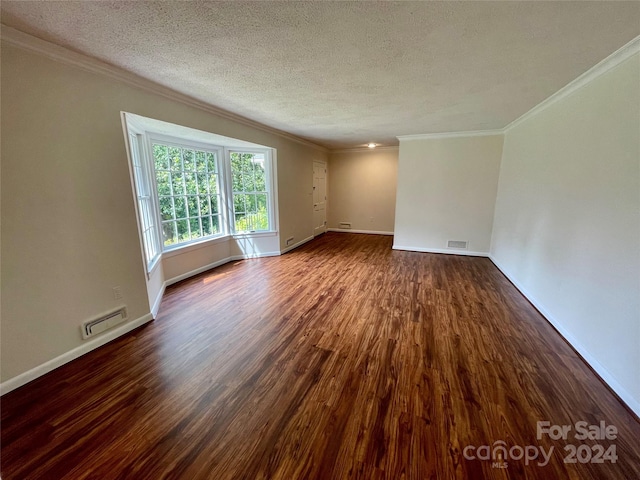 empty room featuring ornamental molding, dark hardwood / wood-style flooring, and a textured ceiling