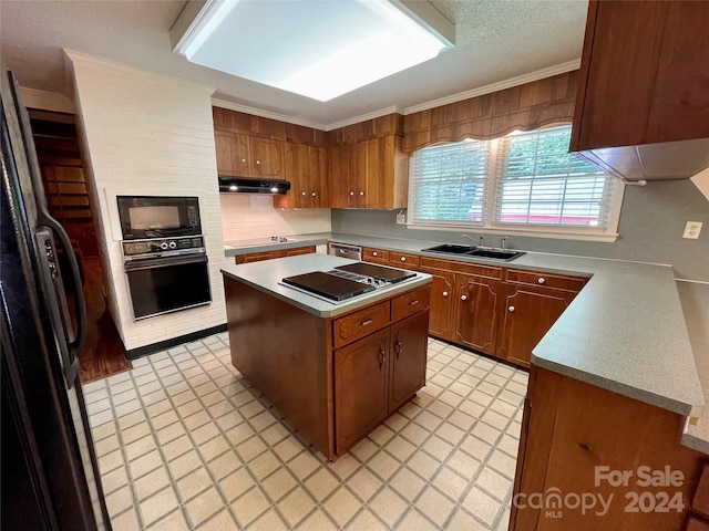 kitchen with ornamental molding, a textured ceiling, black appliances, a center island, and sink