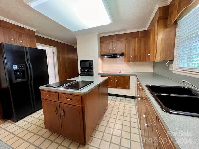 kitchen with ornamental molding, backsplash, black appliances, a kitchen island, and sink