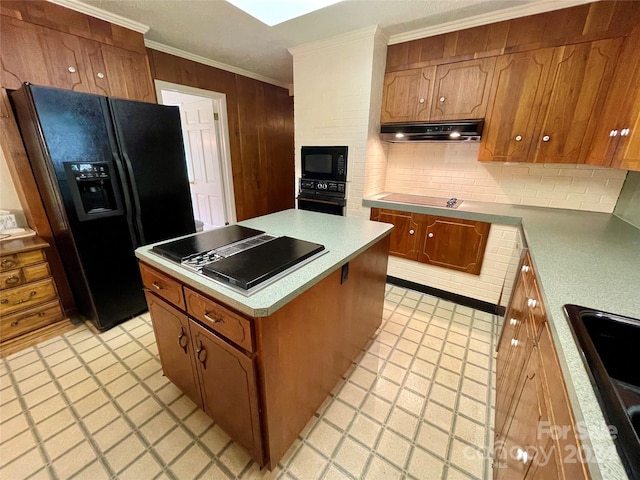 kitchen featuring a skylight, sink, black appliances, tasteful backsplash, and ornamental molding