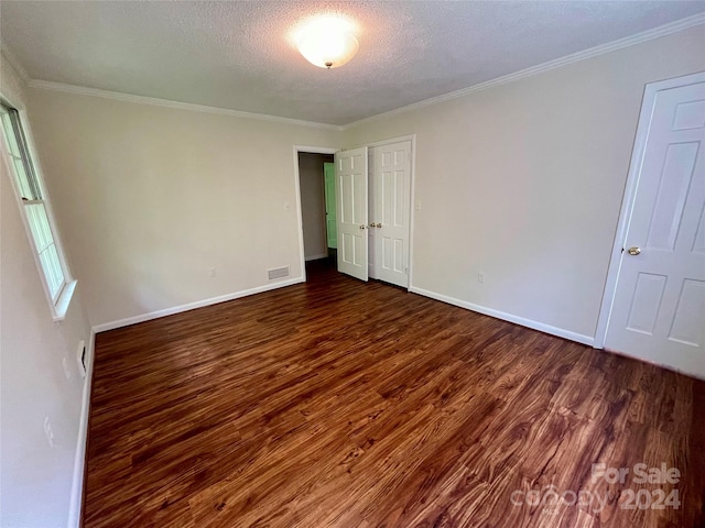 interior space with a textured ceiling, dark wood-type flooring, and ornamental molding