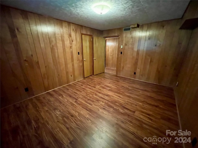 spare room with wood walls and wood-type flooring