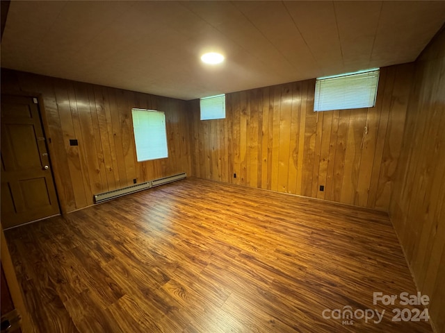 basement with a baseboard radiator, wooden walls, and hardwood / wood-style flooring