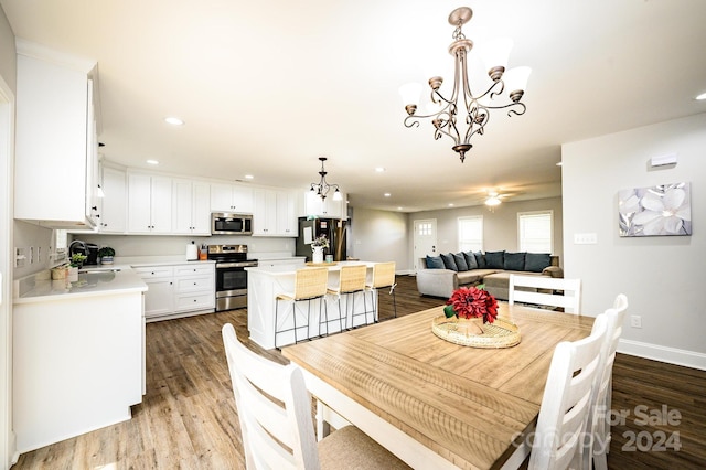 dining space with sink, wood-type flooring, and a notable chandelier