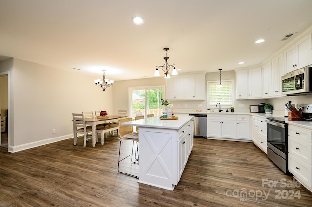 kitchen featuring stainless steel appliances, a center island, decorative light fixtures, white cabinets, and sink