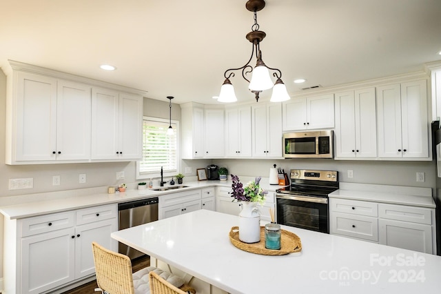 kitchen featuring pendant lighting, appliances with stainless steel finishes, white cabinetry, sink, and a kitchen breakfast bar