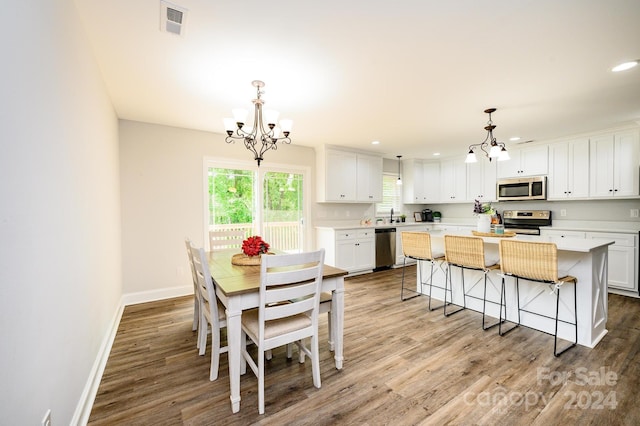 dining space featuring an inviting chandelier, light hardwood / wood-style floors, and sink