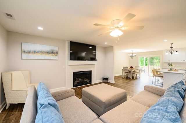 living room featuring ceiling fan with notable chandelier, a fireplace, and hardwood / wood-style flooring