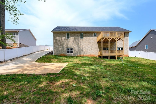 back of property featuring a deck, a patio area, and a yard