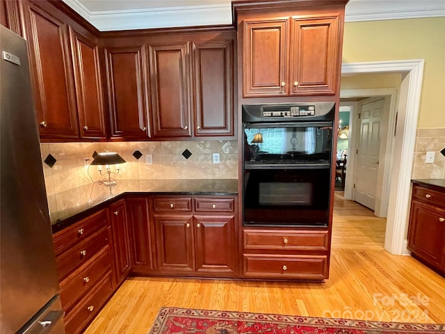 kitchen featuring backsplash, light hardwood / wood-style floors, stainless steel fridge, and double oven