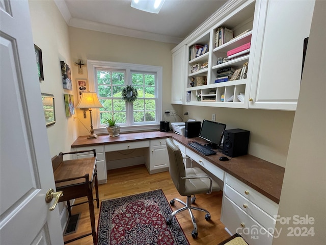 office area with light wood-type flooring, crown molding, and built in desk