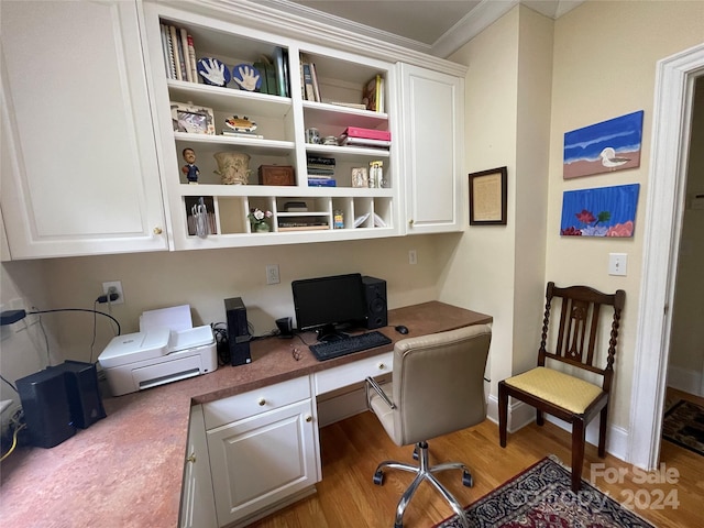 office space with hardwood / wood-style flooring, ornamental molding, and built in desk