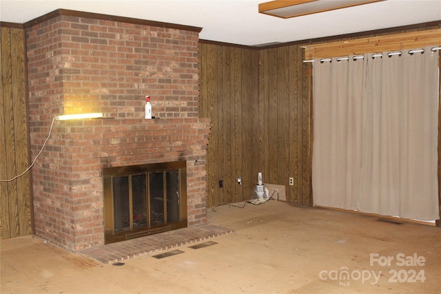 unfurnished living room featuring brick wall, a brick fireplace, wood walls, and crown molding