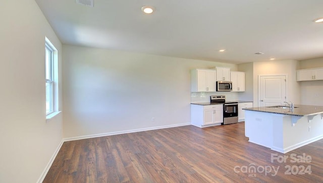 kitchen featuring white cabinetry, stainless steel appliances, a kitchen island with sink, and a breakfast bar area