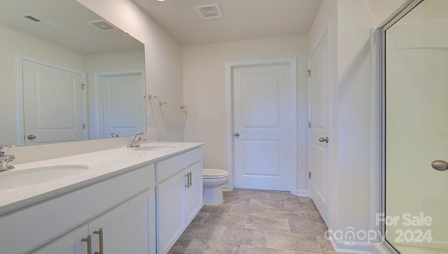 bathroom featuring vanity, toilet, and a shower with shower door