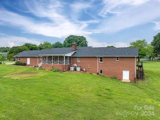 rear view of property with a yard and a sunroom