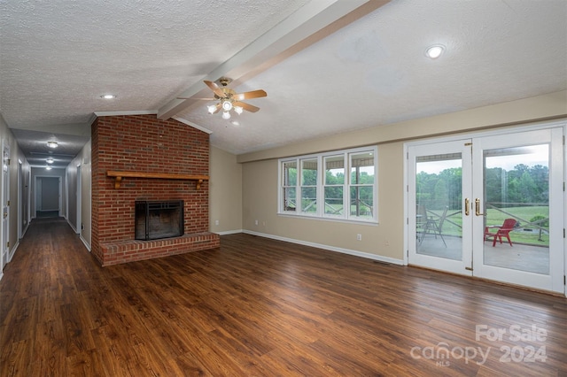 unfurnished living room featuring ceiling fan, a brick fireplace, lofted ceiling with beams, dark wood-type flooring, and french doors