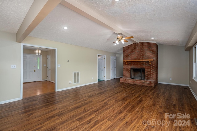 unfurnished living room featuring lofted ceiling with beams, a fireplace, dark hardwood / wood-style floors, ceiling fan, and a textured ceiling