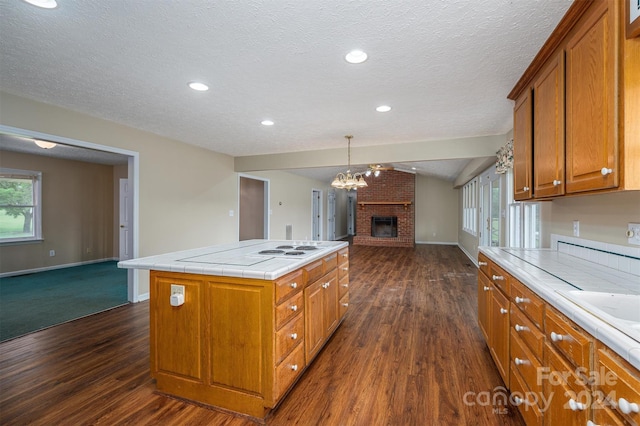 kitchen featuring a kitchen island, a textured ceiling, dark colored carpet, and a fireplace