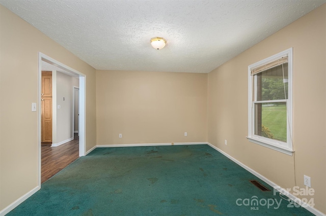 carpeted spare room with a textured ceiling