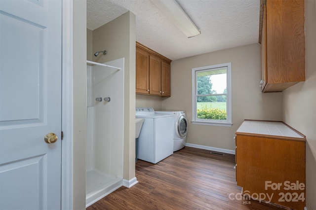 washroom featuring dark hardwood / wood-style flooring, cabinets, a textured ceiling, and washer and dryer