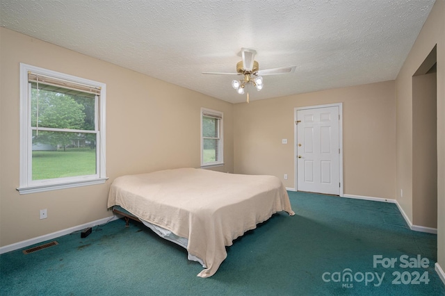 bedroom with carpet, ceiling fan, and a textured ceiling