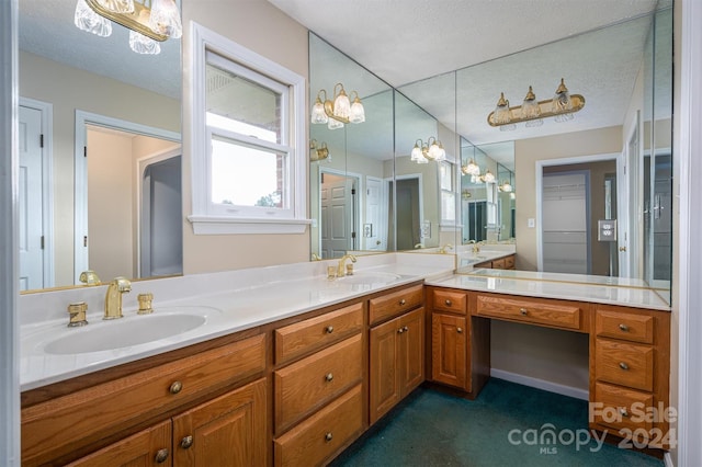 bathroom featuring vanity with extensive cabinet space, dual sinks, and a textured ceiling