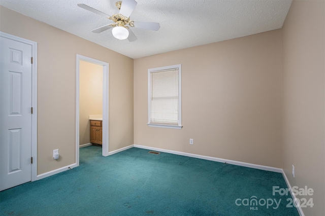 unfurnished bedroom with a textured ceiling, carpet floors, ceiling fan, and connected bathroom