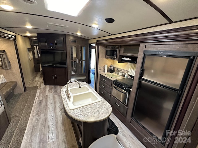 kitchen with hardwood / wood-style floors, black appliances, sink, and a kitchen island with sink