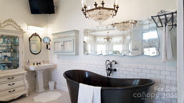 bathroom featuring tile walls, an inviting chandelier, and a bath