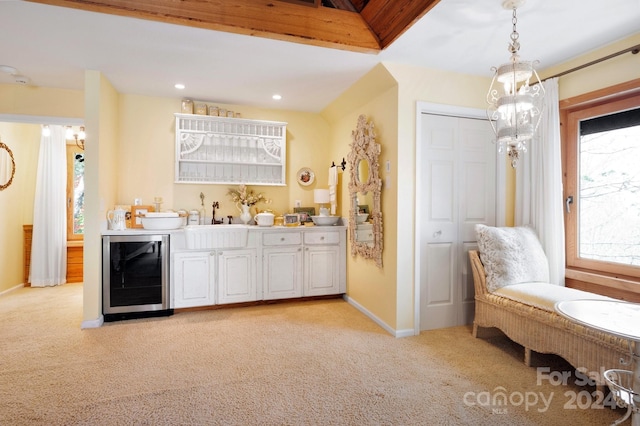 kitchen with wine cooler, light carpet, white cabinetry, and sink