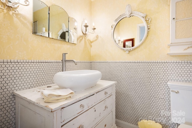 bathroom with vanity, backsplash, toilet, and tile walls