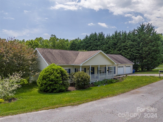 single story home featuring a porch, a garage, and a front yard