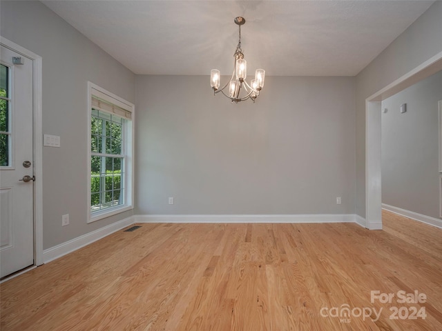 unfurnished room with light hardwood / wood-style floors and an inviting chandelier