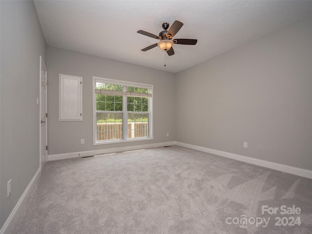 carpeted spare room with ceiling fan and a textured ceiling