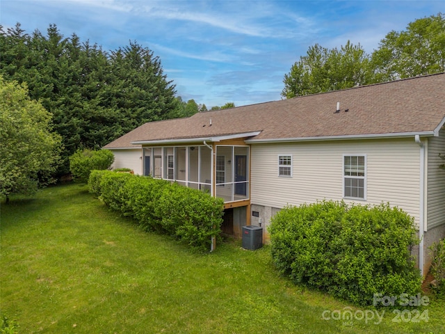 rear view of property with a yard, a sunroom, and central AC unit