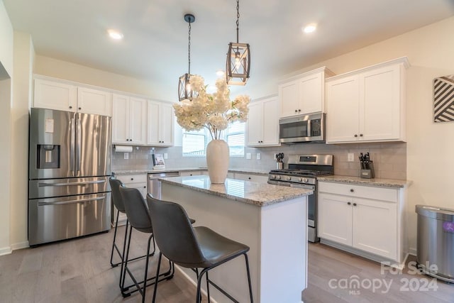 kitchen with a center island, tasteful backsplash, white cabinetry, stainless steel appliances, and light hardwood / wood-style flooring