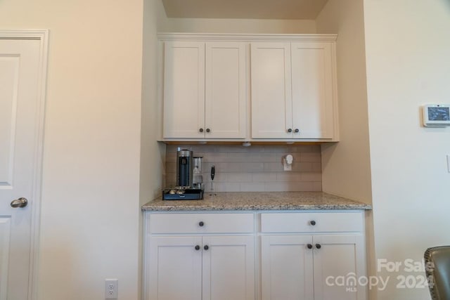 kitchen featuring tasteful backsplash, white cabinetry, and light stone counters