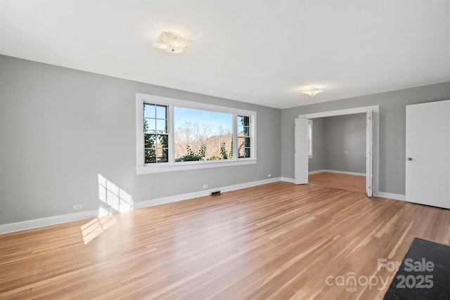 interior space featuring baseboards and light wood finished floors