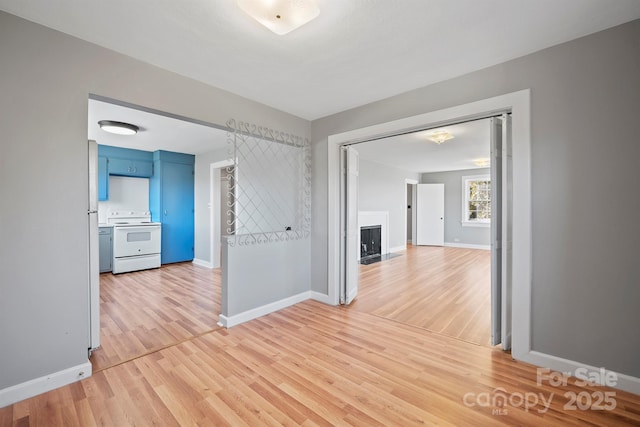 corridor with light wood-style flooring and baseboards