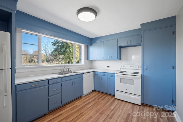 kitchen with blue cabinets, a sink, white appliances, light wood-style floors, and light countertops