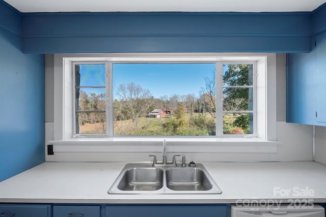 kitchen featuring blue cabinetry, light countertops, and a sink