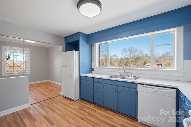 kitchen featuring blue cabinetry, white appliances, light countertops, and a sink