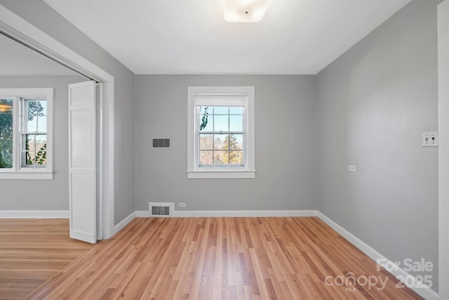 unfurnished room featuring plenty of natural light, baseboards, and visible vents