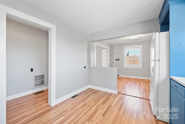 kitchen with visible vents, blue cabinetry, freestanding refrigerator, and light wood-style floors